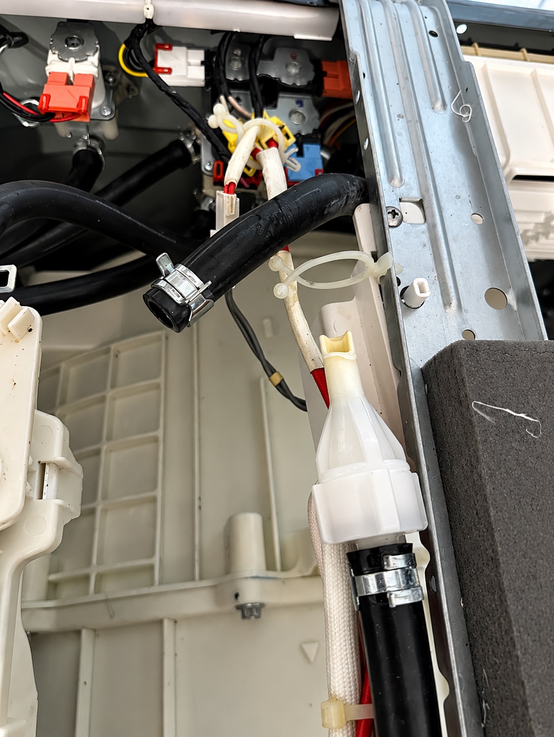 Inside a washing machine's top panel — hoses, wiring and the pressure chamber that feeds the level switch