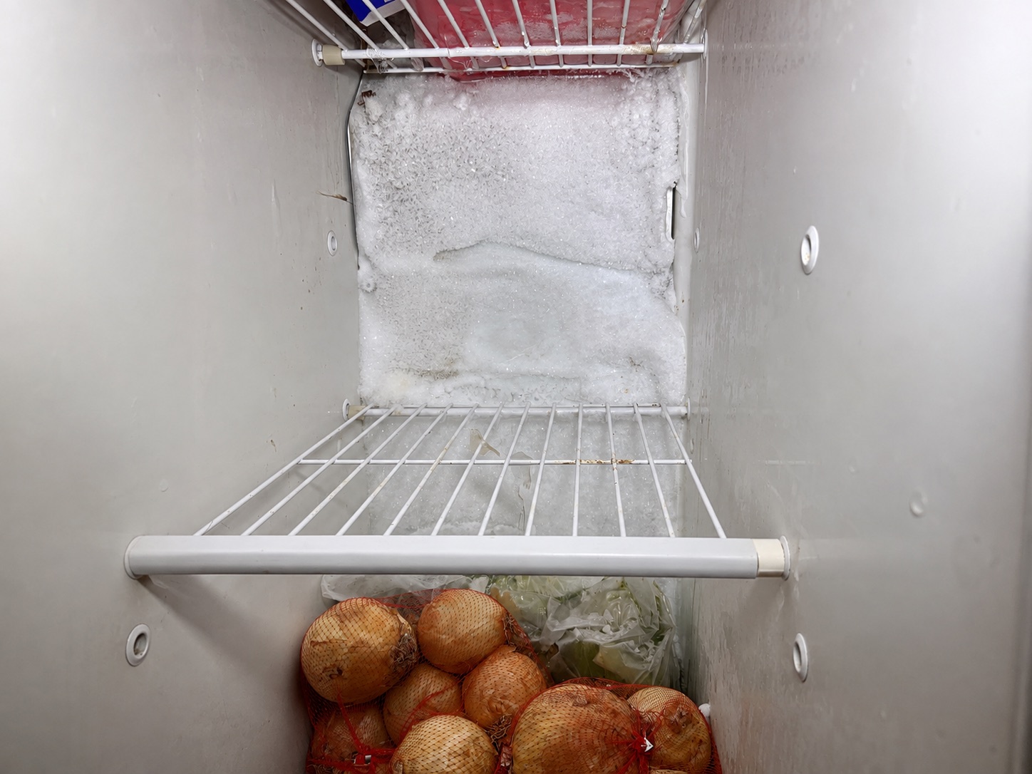 A thick sheet of ice built up across the back wall of a freezer compartment