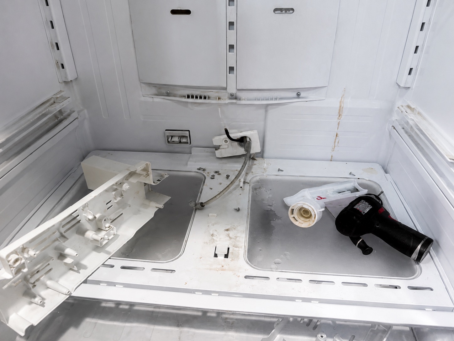 An ice maker assembly dismantled inside the freezer during repair