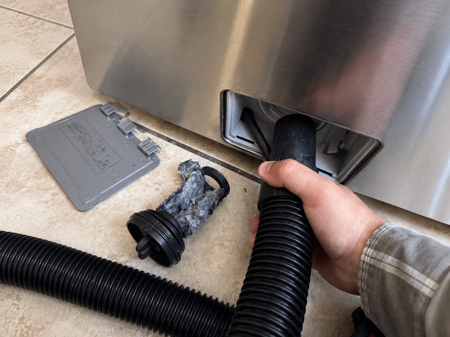 A drain pump filter pulled out of a front-load washer, packed with lint and debris