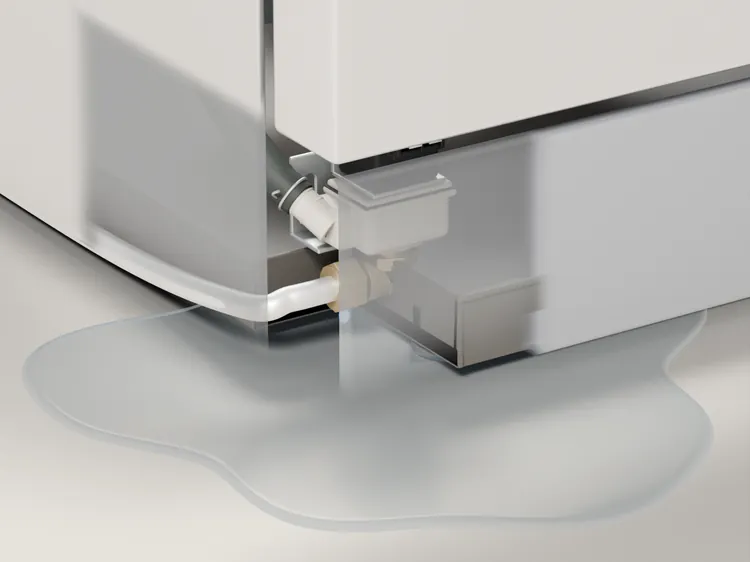 The front bottom corner of the machine: water from the inlet valve connection has spread across the floor in front.